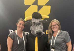 Two SandPoint Consulting team members posing with the BlackLine mascot at Beyond the Black 2025.