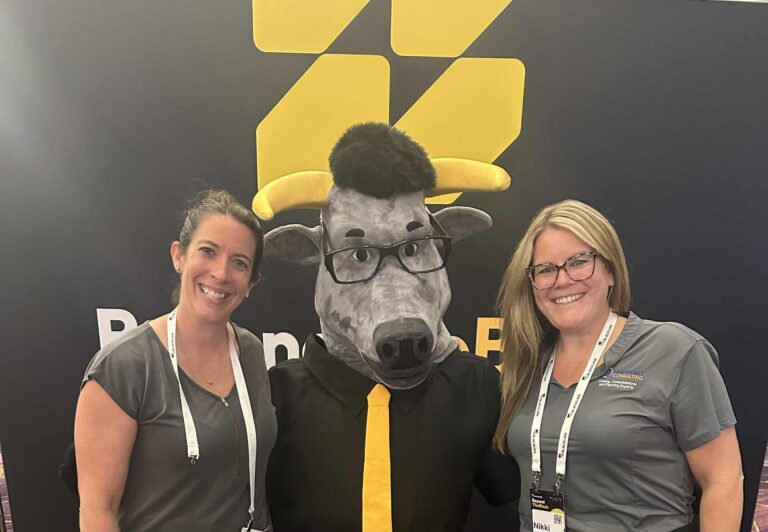 Two SandPoint Consulting team members posing with the BlackLine mascot at Beyond the Black 2025.